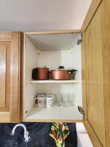 een kast met wat potten, mokken en glazen bij Apartamento Vca Paraguay in Villarrica