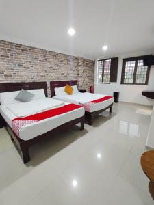 two beds in a room with a brick wall at J Hotel Masjid India KL in Kuala Lumpur