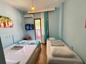 two twin beds in a room with a window at Yeşim Pansiyon in Çeşme