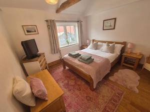 ein Schlafzimmer mit einem Bett und einem Fernseher darin in der Unterkunft Lime Kiln Quay Cottage in Woodbridge