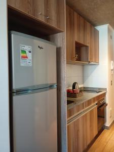 a white refrigerator in a kitchen with wooden cabinets at Departamento Barcelona in Temuco