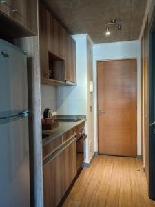 a kitchen with wooden cabinets and a wooden door at Departamento Barcelona in Temuco