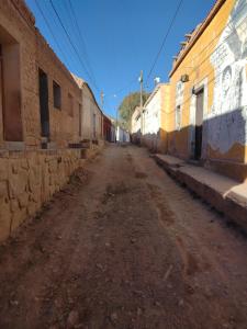 an empty dirt road in an alley between buildings at Casa La Candelaria in Tilcara