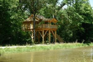 a tree house sitting on the side of a river at Les Cabanes des Blots in La Bussière +9 photos