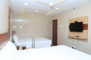 甘吉布勒姆TCS Residency的一间有两张床和一台平板电视的酒店房间 更多24张照片