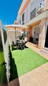 un patio con tavolo, sedie e ombrellone di Casa SOL y MAR junto a la PLAYA a Sanlúcar de Barrameda