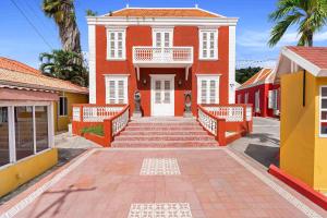a red house with a white door and stairs in front at The Ritz Hostel in Willemstad