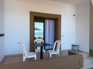 a dining room with a table and white chairs at Palmanova Beach Mardok in Vlorë