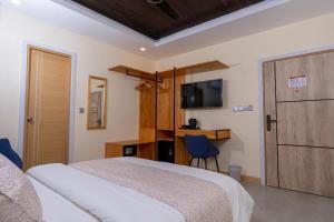 a bedroom with a bed and a desk and a television at Fen Villa in Dharavandhoo