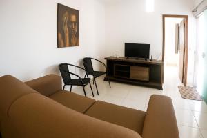 a living room with a couch and a tv at Apartamento charmoso 3/4 in Ilhéus