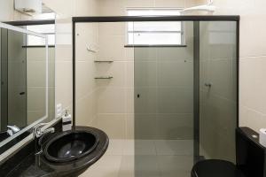 a bathroom with a sink and a glass shower at Apartamento charmoso 3/4 in Ilhéus +17 photos