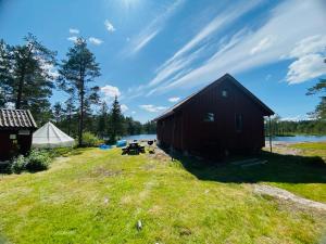 a red barn on a grass field with a tent at Fredelig og landlig lavvoferie in Møkjåland