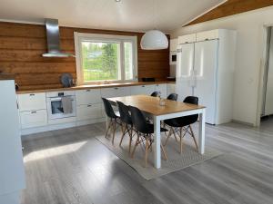a kitchen with a wooden table and black chairs at Villa beach star in Ranua