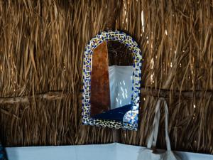 a mirror on a straw wall with a blue at Natural Lodge in Dahab
