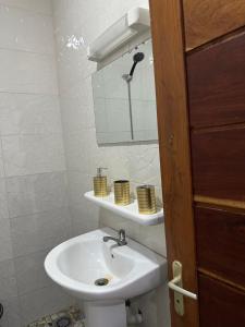 Un baño blanco con lavabo y espejo. en Lune Rose ApparT, en Cotonou