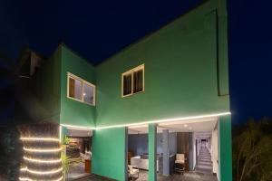 a green house with lights on it at night at Skazka beach resort in Mandrem