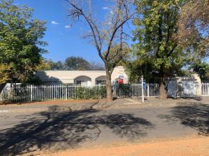 a white fence in front of a house with a tree at B&B at Bloem in Bloemfontein