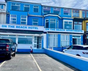 a blue building with cars parked in front of it at On The Beach Apartments in Blackpool