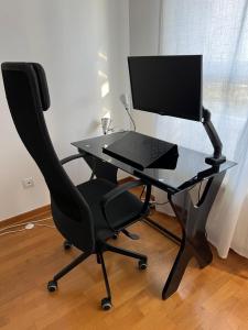 Novi BeogradZen Suite的一张带电脑显示器和椅子的黑桌