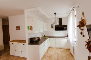 a kitchen with white cabinets and a wooden floor at VacationClub - Leśny Dom 16A Apartament 14 in Karpacz