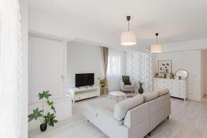 a white living room with a white couch and a tv at City Center Accommodation 111 in Reşiţa