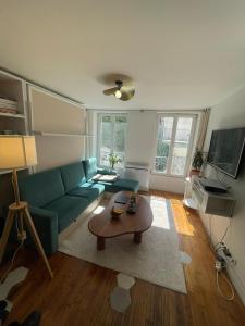 uma sala de estar com um sofá verde e uma mesa em Studio Cosy au charme Parisien - Butte aux cailles em Paris