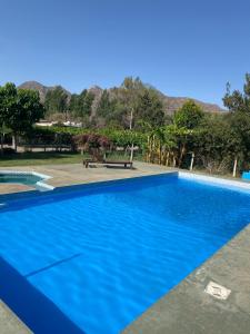 a blue swimming pool with a bench and mountains in the background at cabañas las viñas in Anguinán