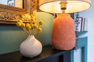 deux vases assis sur une table à côté d'une lampe dans l'établissement La Fine Bulle, Appartement de Charme au cœur de Reims, à Reims
