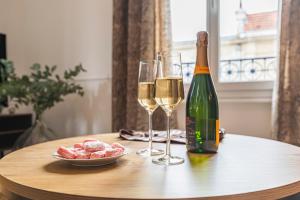 - une table avec deux verres de vin et une assiette de nourriture dans l'établissement La Fine Bulle, Appartement de Charme au cœur de Reims, à Reims
