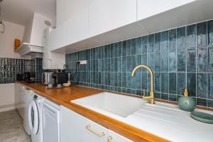 Il comprend une cuisine avec un évier et un mur carrelé vert. dans l'établissement La Fine Bulle, Appartement de Charme au cœur de Reims, à Reims 12 autres photos