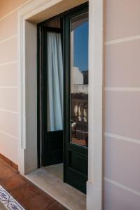 eine grüne Tür mit einem Fenster in einem Gebäude in der Unterkunft Le Stanze del Monsignore in Novoli