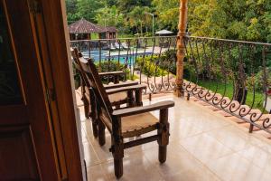 two wooden chairs sitting on a balcony with a pool at Hotel San Sebastian del Tonusco in Santa Fe de Antioquia