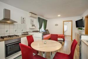 a kitchen and living room with a wooden table and red chairs at Kuća za odmor Sparta in Dugo Selo