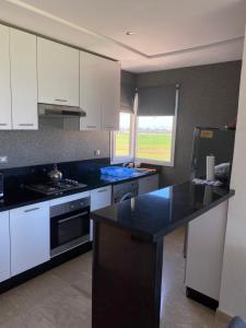 a kitchen with white cabinets and a black counter top at Résidence Evasion in Bouznika