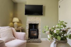 a living room with a fireplace with a tv on the wall at Flat 2 Martins House in Stow on the Wold