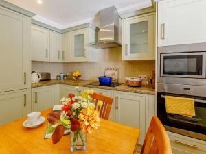 a kitchen with a wooden table with a vase of flowers at 2 Bed in Bridport 88614 in Chideock +19 photos