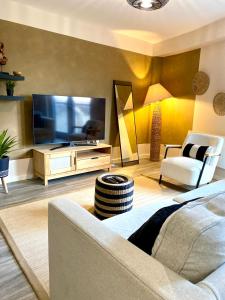 a living room with a television and a couch and chairs at Safari 2 Bedroom Condo with Free Secure Parking in Manchester