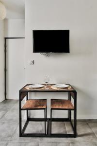 een tafel met twee stoelen en een tv aan de muur bij O Garibaldi in Lyon