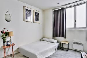 een witte slaapkamer met een bed en een raam bij O Garibaldi in Lyon