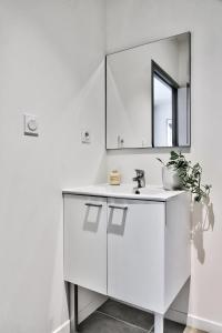 een witte badkamer met een wastafel en een spiegel bij O Garibaldi in Lyon