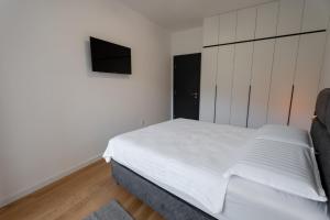 Apartman VISTA FIUME في تريبينيي: غرفة نوم بسرير أبيض وتلفزيون