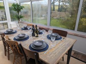 a wooden table with plates and wine glasses on it at Fig Tree Cottage - Corfe Castle in Corfe Castle