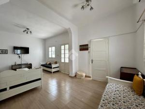 a white room with a bed and a tv and a door at Villa atypique Sousse Quartier chic in Sousse