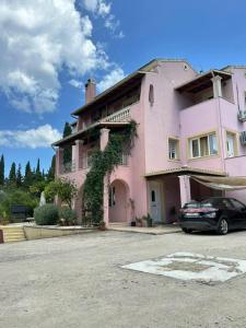 a pink house with a car parked in front of it at villa olga-corfu in Kynopiástai