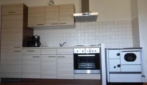 eine Küche mit weißen Schränken, einem Herd und einer Mikrowelle in der Unterkunft Ferienwohnung Monika in Bad Ischl