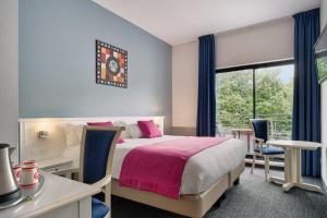a bedroom with a bed and a desk and a window at Hôtel Marso in Amnéville