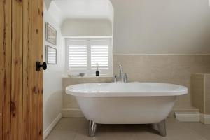 una vasca bianca in un bagno con finestra di The Roost a Quenington Altre 17 foto