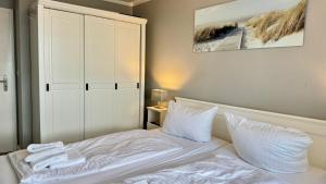 a bedroom with a bed with white sheets and pillows at MEERzeit in Westerland (Sylt)