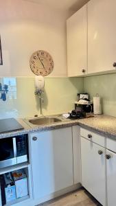 a kitchen with white cabinets and a clock on the wall at MEERzeit in Westerland (Sylt) +10 photos