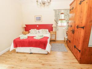 a bedroom with a bed with a red headboard at 2 The Stables in Haven Street